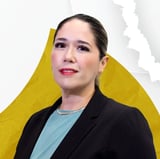 Professional portrait of an Asian woman wearing a black blazer and light blue shirt against a yellow and white geometric background