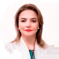 Professional headshot of a woman with shoulder-length brown hair wearing a white blazer over teal top