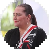 Woman with pulled-back hair wearing black top with red and white striped collar detail